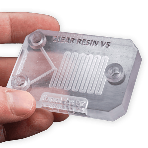 A hand holding a part printed with Formlabs Clear Resin V5.